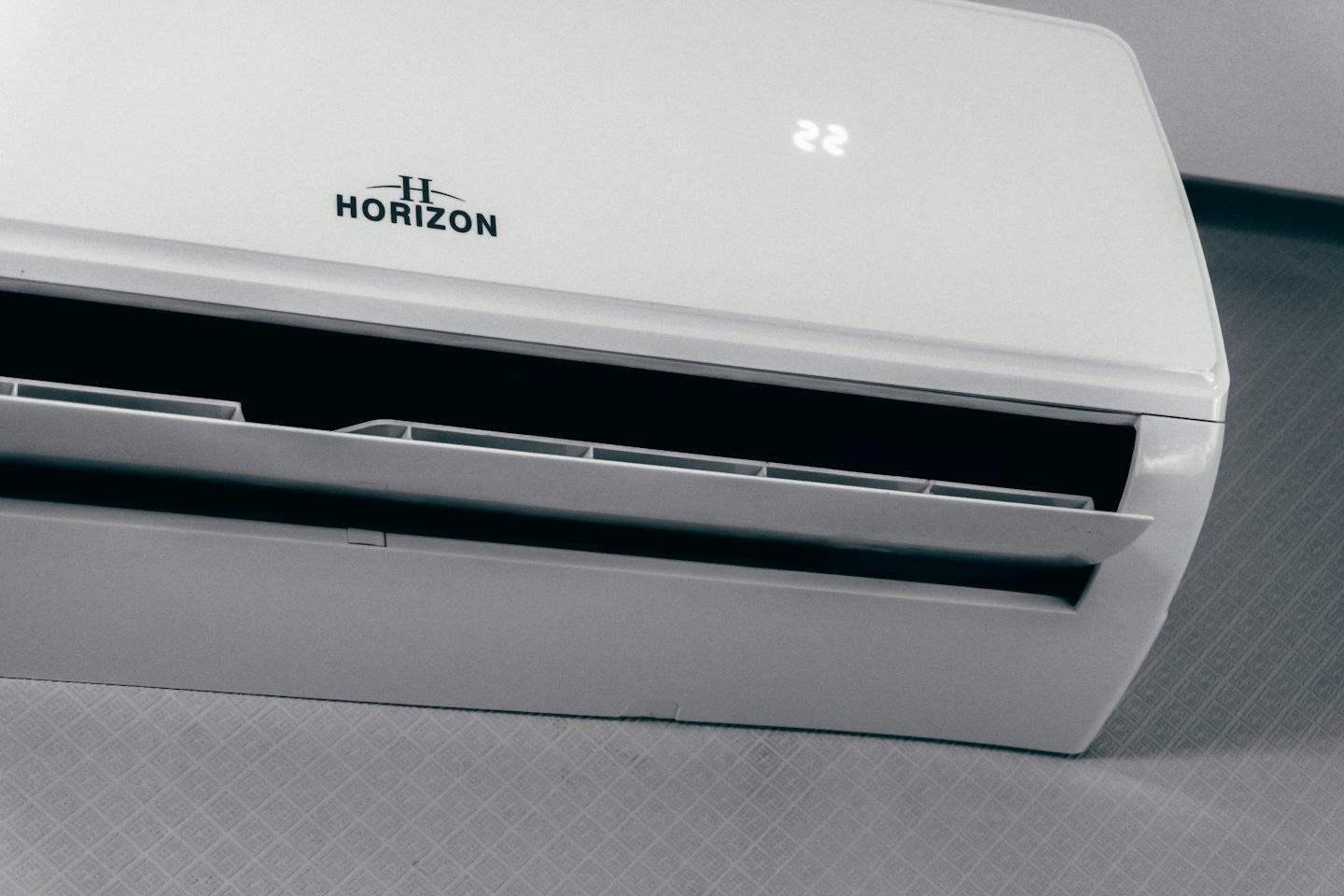 Moderne split-airconditioner met open ventilatieopeningen die 22 graden aangeven.